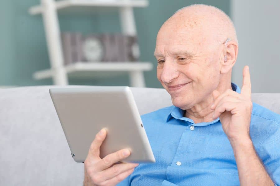 un senior connecté, regardant sa tablette numérique