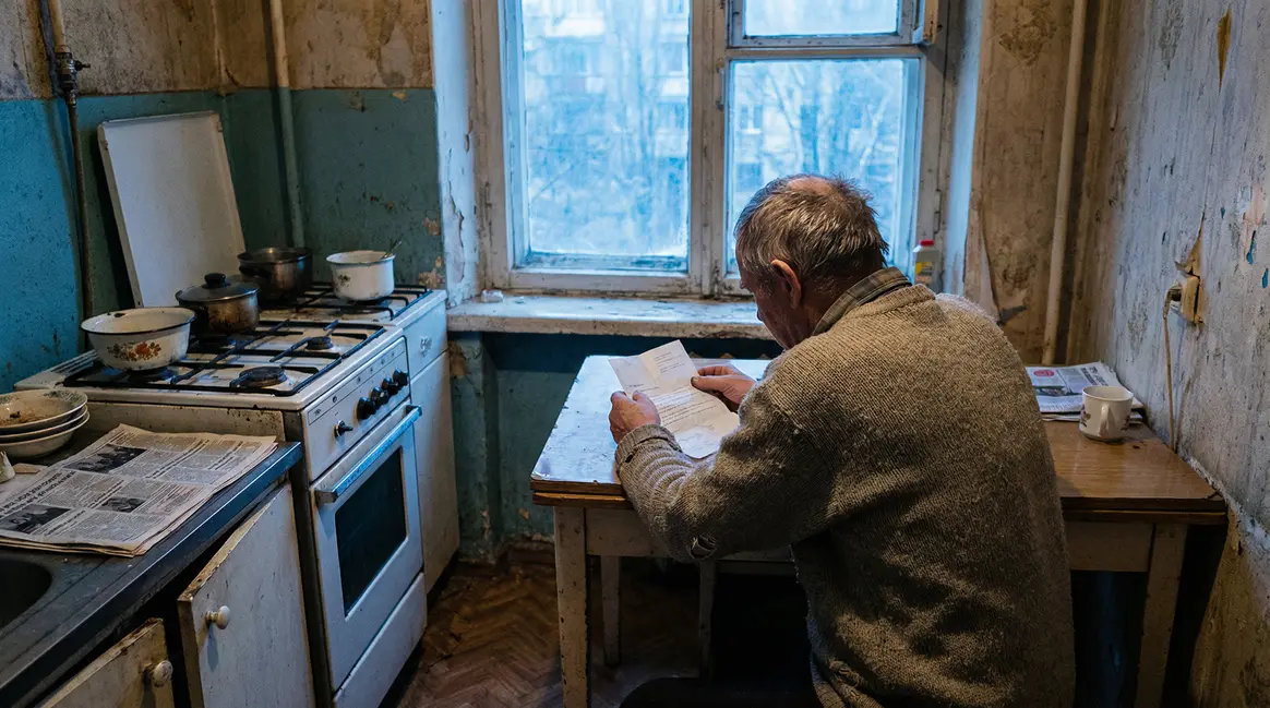 Retraité routier anxieux tenant lettre de pension dans cuisine