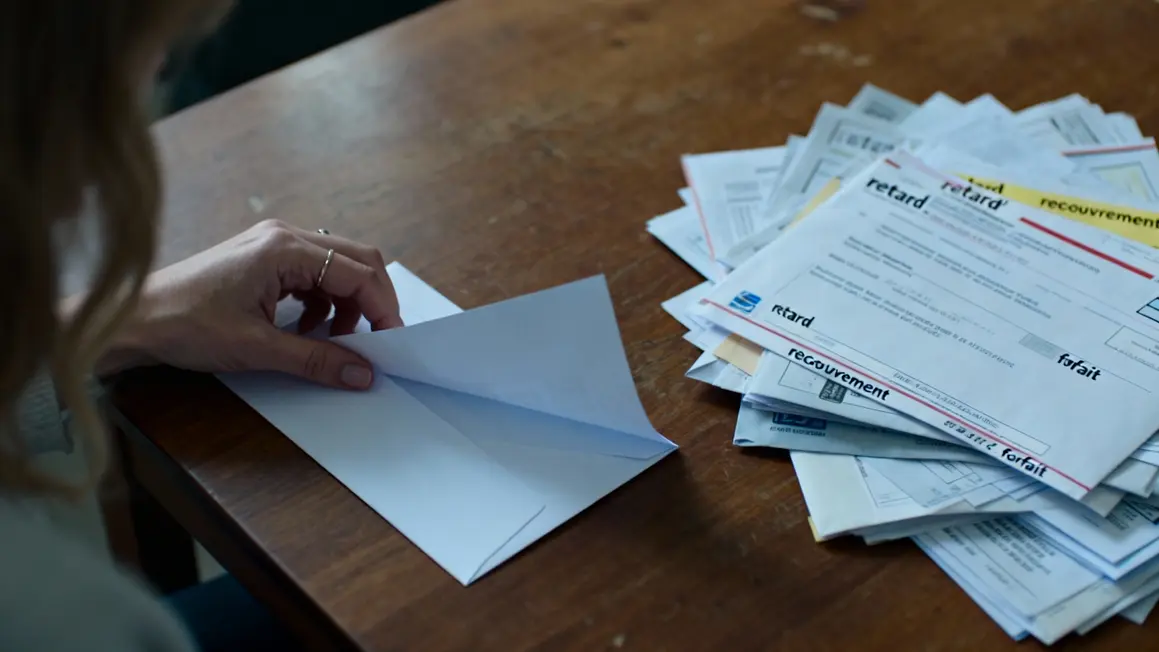 Main ouvre enveloppe dette santé VIH courriers empilés
