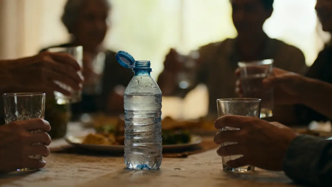 famille servant bouteille d eau ouverte table
